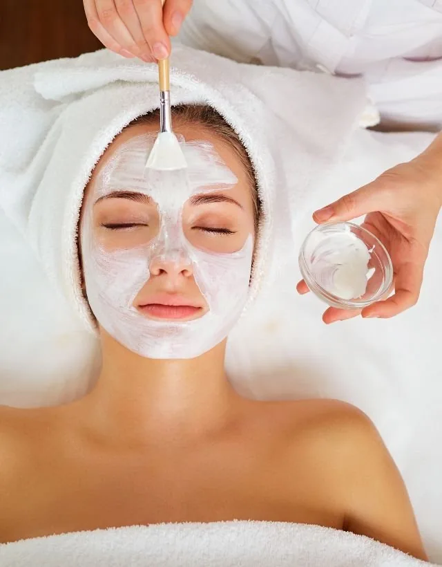 A clay treatment mask being applied during a facial