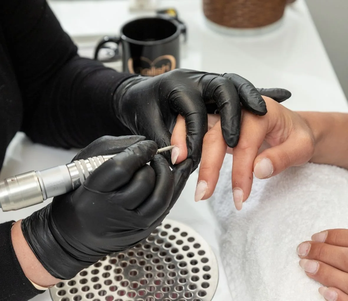 A nail technician shaping and refining a gel manicure
