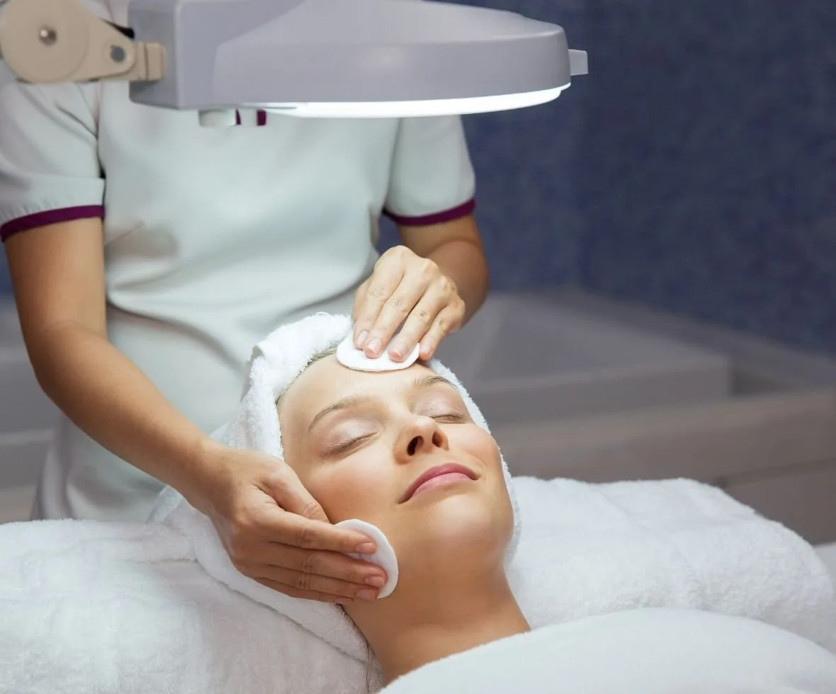 An esthetician working under a treatment lamp